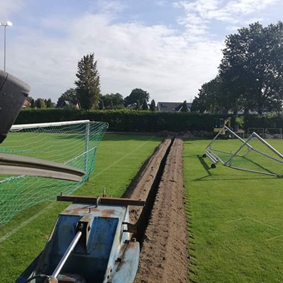 Graben für Bewässerungsanlage zwischen zwei Rasensportplätzen.